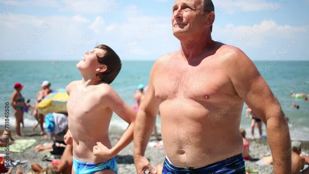 A man with his grandson stands on beach with hands on side A man with his grandson stands on beach with hands on side