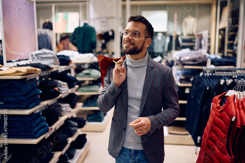 Young smiling man shopping in clothing store. photo