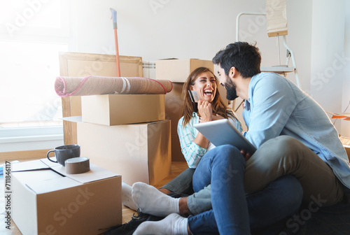 Enthusiastic millennial couple feeling excited using digital tablet, holding credit card, satisfied with online payment possibilities,rejoicing approved loan during renovation process in new apartment photo