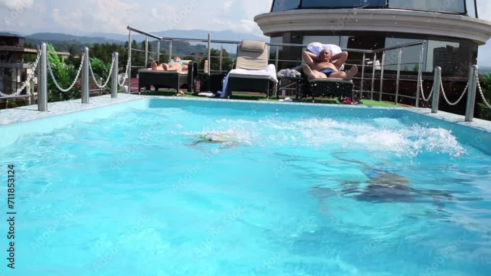 swimming pool on rooftop with children and two sunbathing adults swimming pool on rooftop with children and two sunbathing adults