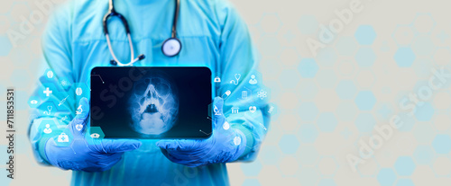 The doctor holds a tablet and examines an x-ray of paranasal sinuses, deviation of the nasal septum, localization of nasal polyps, shows the x-ray of the skull with waters projection photo