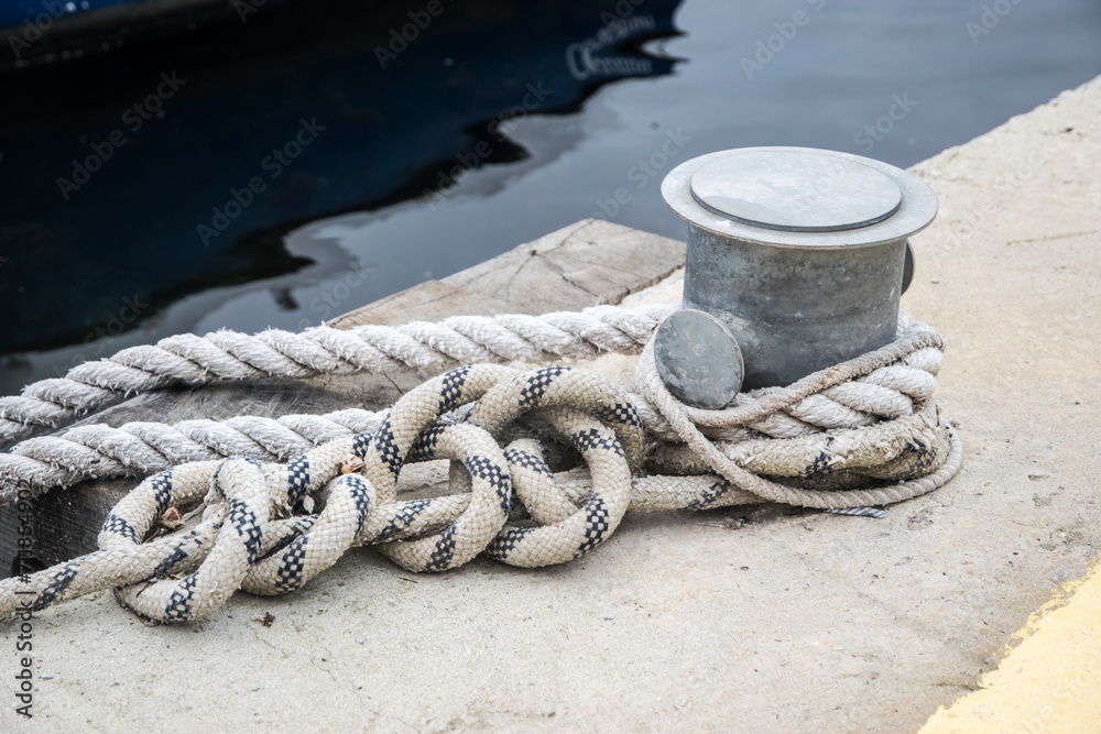 Fototapeta premium Metal dock mooring pole with rope for securing fishing boats closeup