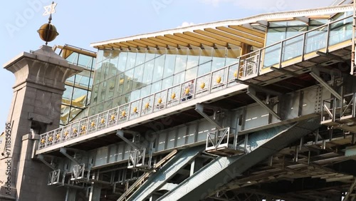 Under view of man going on footbridge with glass walls in city photo