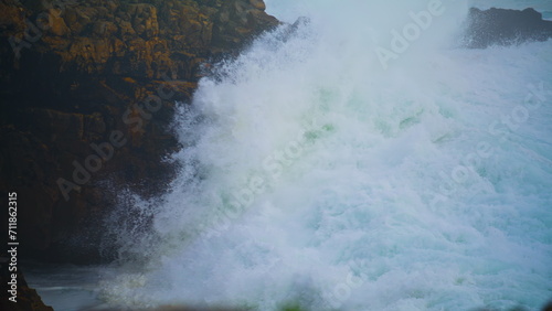 Violent ocean waves crashing wild cliff closeup. Seashore storm crashing rocks
