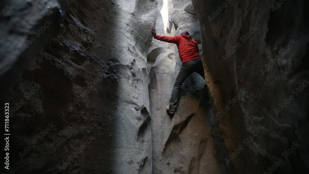 Mountaineering. Extreme sports. View of a man climbing the rocky cliffs deep inside the canyon. View of the dark rock walls. Mountaineering. Extreme sports. View of a man climbing the rocky cliffs deep inside the canyon. View of the dark rock walls.