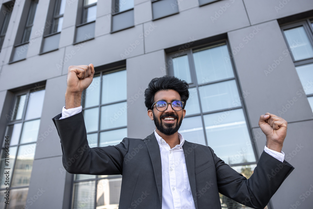 Waist up of an excited successful hindu businessman near the office building Waist up of an excited successful hindu businessman near the office building