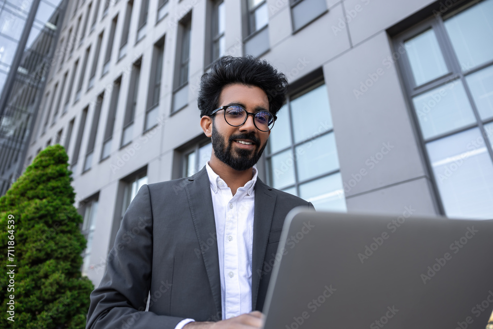 Brunette young businessman working on laptop and feeling contented Brunette young businessman working on laptop and feeling contented