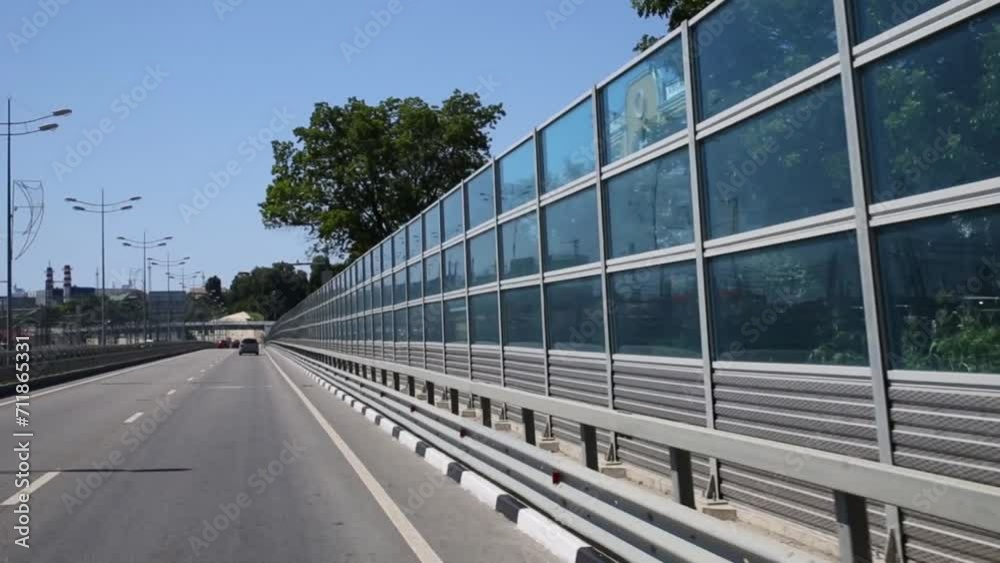 Moving cars on modern road with transparent wall at summer Moving cars on modern road with transparent wall at summer