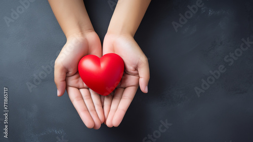 Top view photo of hands holding red heart on black background  healthcare  love  organ donation  mindfulness  wellbeing  family insurance and CSR concept  World Heart Day.