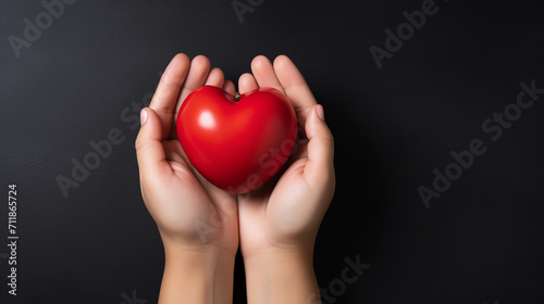 Top view photo of hands holding red heart on black background  healthcare  love  organ donation  mindfulness  wellbeing  family insurance and CSR concept  World Heart Day.