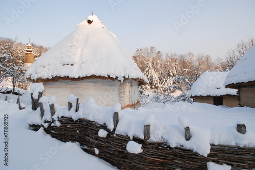 
A wooden roof with a reed roof covered with snow. Winter. Everything is white from snow.