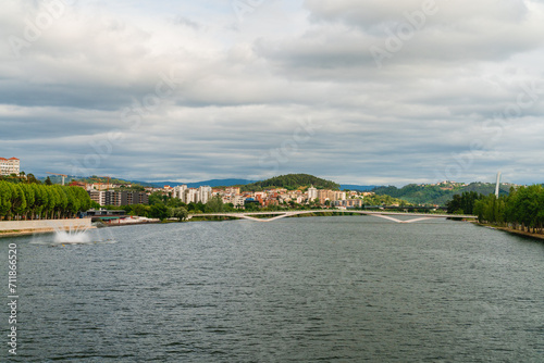 Landscape view of Coimbra bridge upon Mondego river in Portugal with a summer cloudy sky day