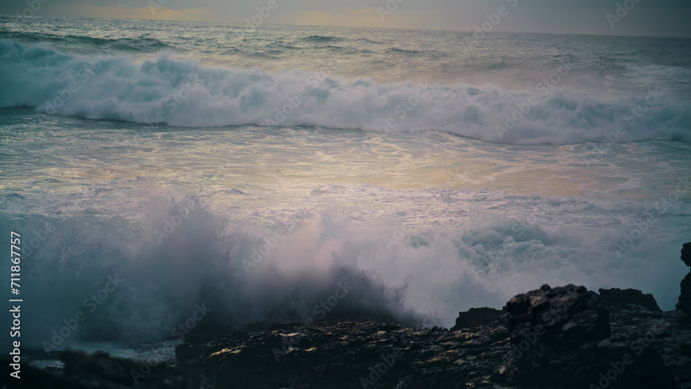 Fototapeta premium Foaming waves breaking coastline stones close up. Powerful ocean rolling shore