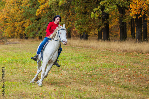 A pretty young woman and a white horse going around the forest