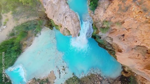 Man sits on rock above waterfall Havasu Falls at autumn day