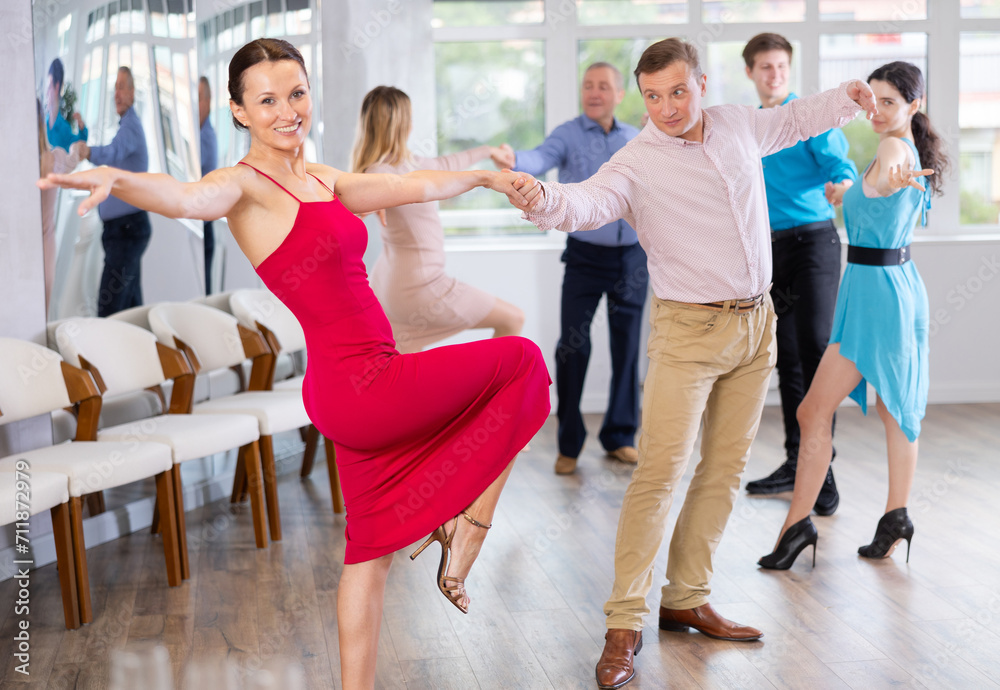 Fototapeta premium Positive adult pairs practicing vigorous jive movements in dance class