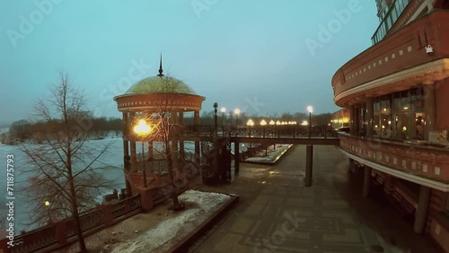 Quay with bridge to rotunda near dwelling house and icy river photo