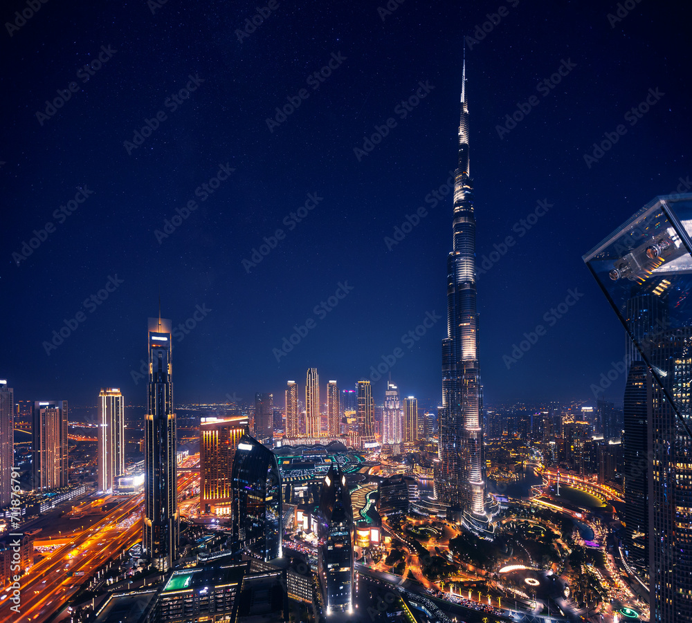 Fototapeta premium Aerial top view Dubai, night amazing skyline cityscape with illuminated skyscrapers, neon color. Modern downtown United Arab Emirates, sky with stars
