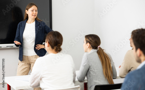 Positive successful woman near interactive board conducting business training for audience in classroom