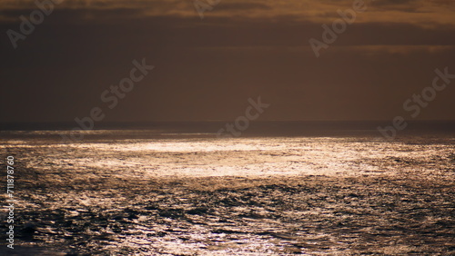 Ocean surface reflecting sunlight at cloudy sky. Peaceful endless sea landscape.