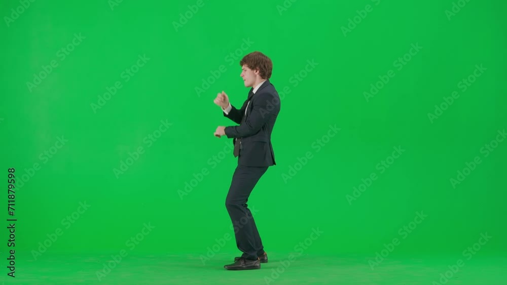 Portrait of male model in suit on chroma key green screen. Handsome young businessman in trendy suit posing at the camera and dancing, side view. Portrait of male model in suit on chroma key green screen. Handsome young businessman in trendy suit posing at the camera and dancing, side view.