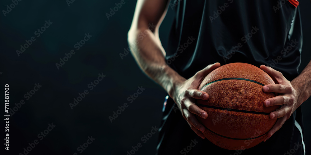 A focused athlete in a dark jersey holds a basketball against a dark background, emphasizing the readiness and determination for the game. A focused athlete in a dark jersey holds a basketball against a dark background, emphasizing the readiness and determination for the game.