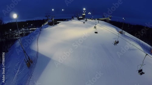 People ascend on chairlift, ride on ski and snowboards by slope photo