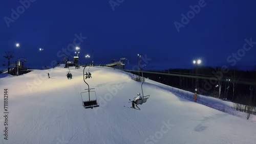 People ascend on chairlift to top of snow slope at winter  photo
