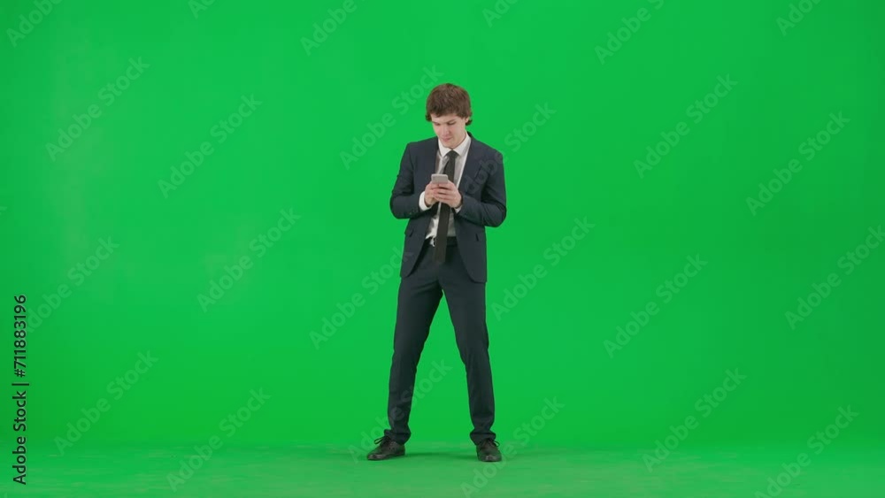 Portrait of male model in suit on chroma key green screen. Handsome young businessman in trendy suit holding smartphone texting and dancing Portrait of male model in suit on chroma key green screen. Handsome young businessman in trendy suit holding smartphone texting and dancing