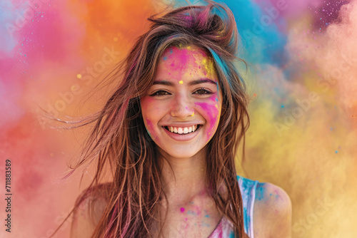 Happy adult girl with paint on face celebrating Holi festival in India. Portrait of young woman having fun on colorful powder background. Concept of color, party, travel people