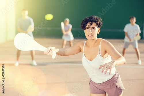 Young sporty woman performing basic strokes during paleta fronton group training