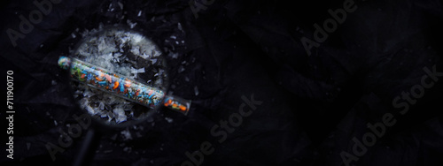 A macro shot of microplastics seen through a magnifying glass with copy space on the right. A close-up of microplastics particles against a black fabric background. Concept for water pollution and glo photo