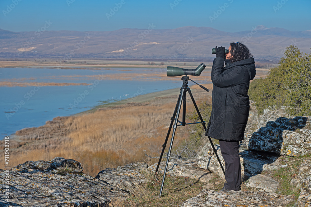 A woman birdwatching with binoculars.