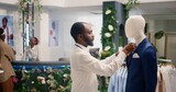 Employee in thrift shop arranging cheap and stylish blazer on mannequin. Retail assistant in second hand clothing store tidying up pocket square and lapels on formal attire garment