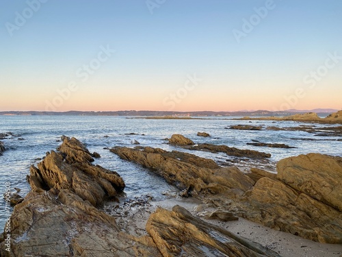 Sunset at the beach. Dawn on the beach. Waves curling on the rocky shore. Ocean view at low tide.