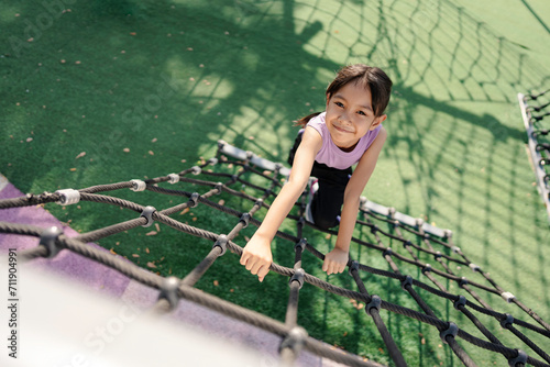 A girl is playing climbing and exercising at the playground.