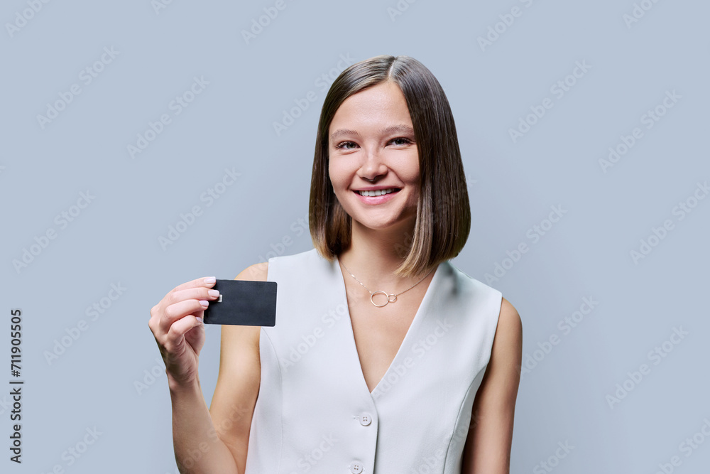 Young woman with bank credit card in hands on grey studio background Young woman with bank credit card in hands on grey studio background