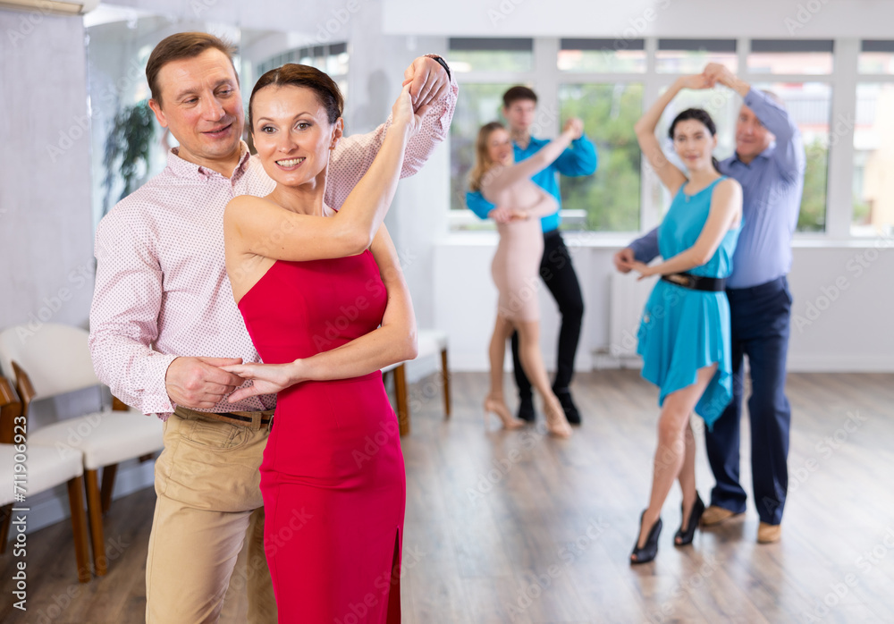 Fototapeta premium Group of different ages active people in festive clothes dancing dance movements in modern studio