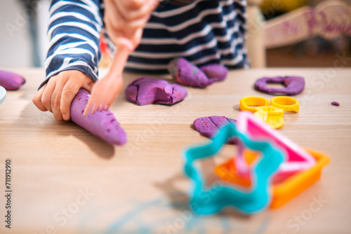 Manos de niña de 2 años jugando con plastilina casera y moldes. Jugar con la plastifica en casa, juguetes educativos para niños Montessori. Juegos creativos para niños pequeños. 