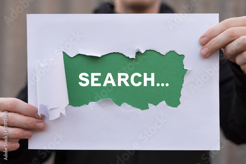 Man holding white and green sheets of paper with text: SEACRH. Search information and web navigation business marketing concept. Internet browser search suggestions. photo