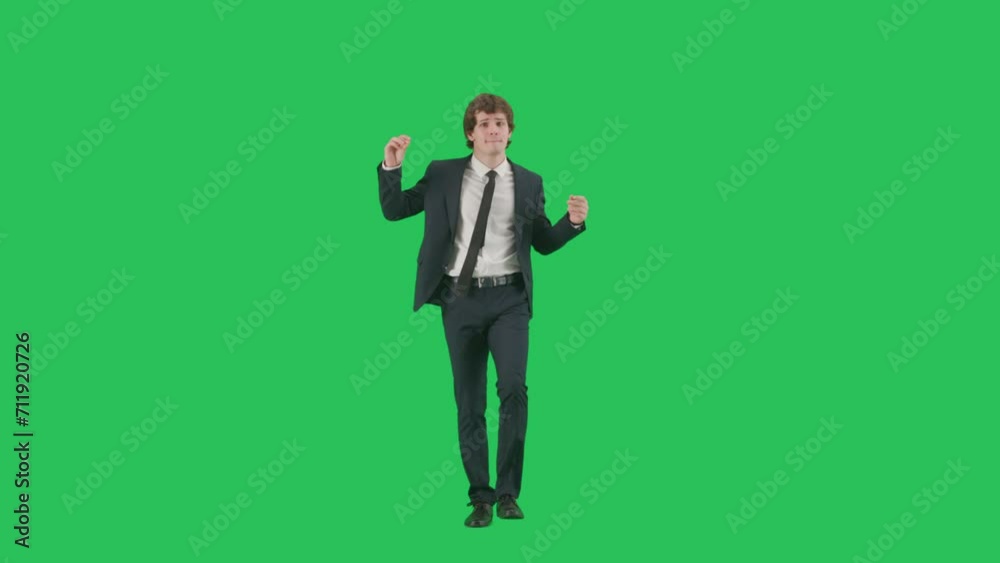 Portrait of male model in suit on chroma key green screen background. Friendly young businessman in trendy suit walking smiling dancing at camera.