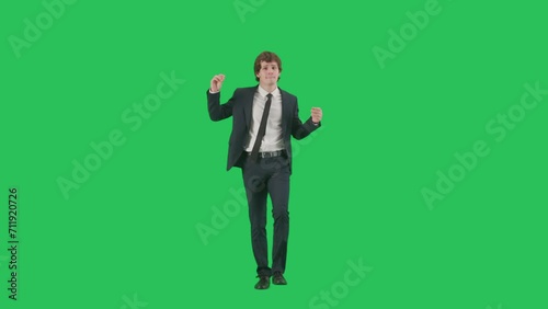 Portrait of male model in suit on chroma key green screen background. Friendly young businessman in trendy suit walking smiling dancing at camera.