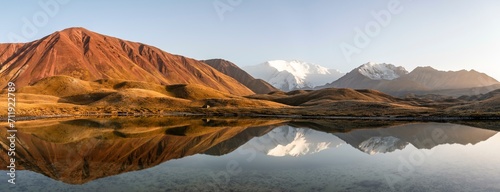 White glaciated and snowy mountain peak Pik Lenin at sunset, mountains reflected in a lake between golden hills, Trans Alay Mountains, Pamir Mountains, Osh Province, Kyrgyzstan, Asia photo