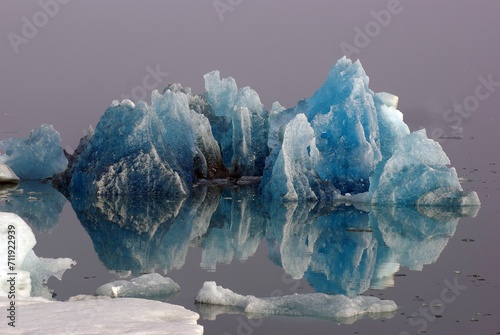 Blue iceberg reflected in the water, mountains rising out of the mist, Joekulsarlon, glacier lagoon, Scandinavia, Iceland, Europe