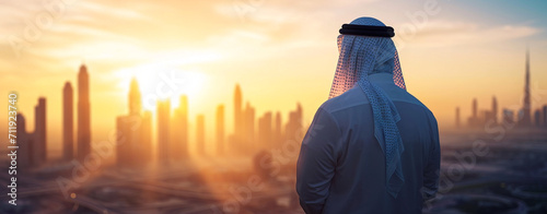 Arab man standing in front of modern high-rise city.