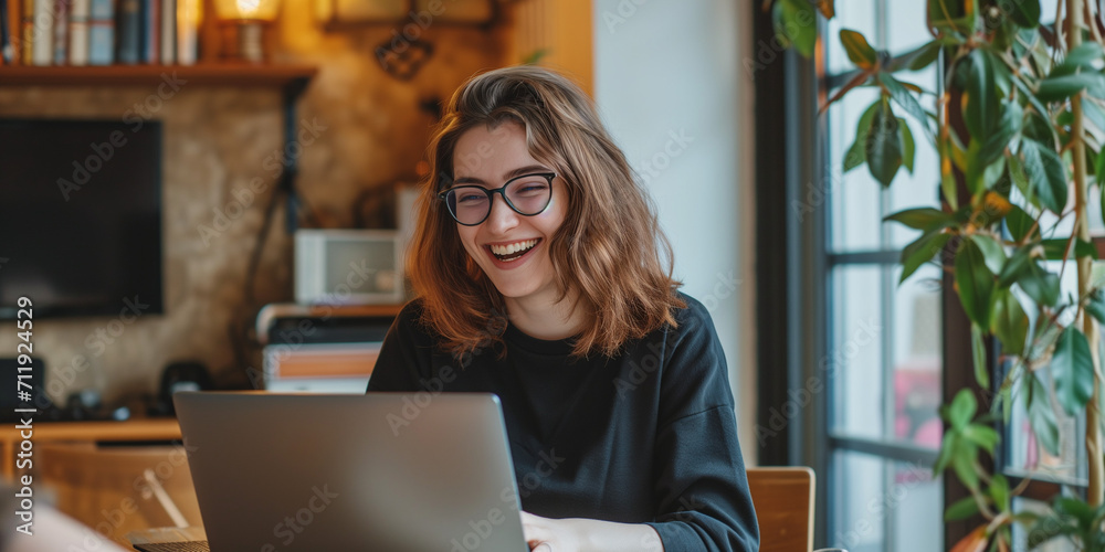 a smiling young woman working on her laptop - obrazy, fototapety, plakaty 