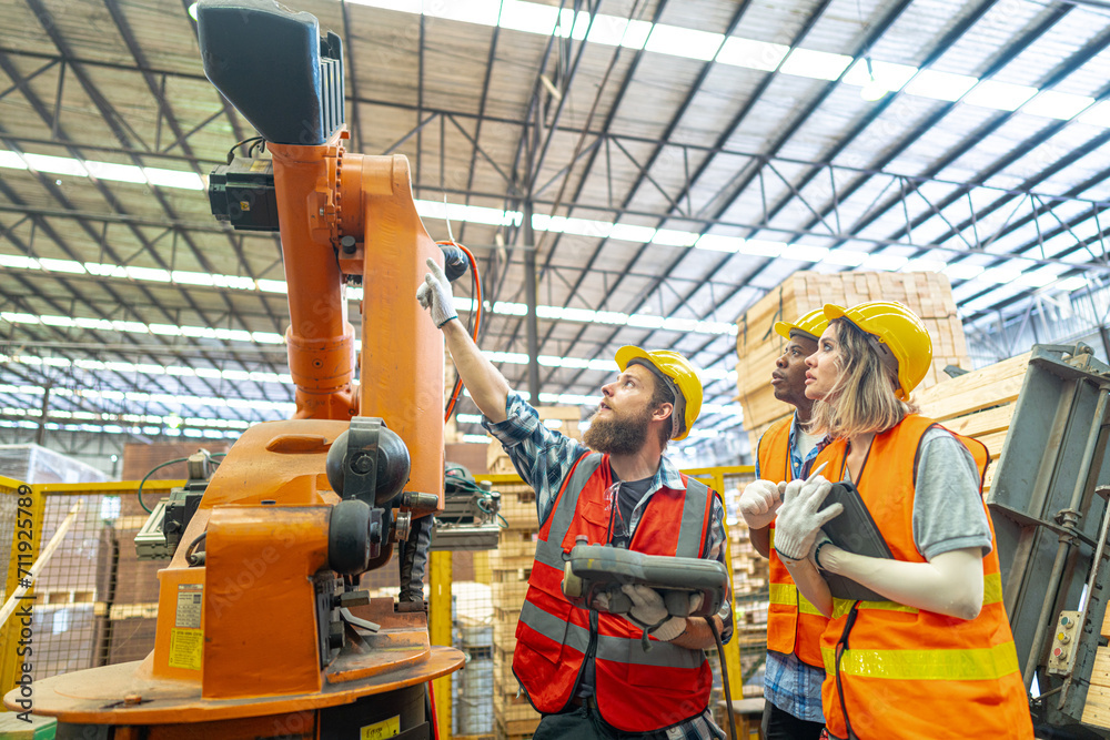 team Engineers standing by robotic arm and operating machine in factory. worker man control on tablet. Workers work at heavy machine robot arm. High-tech robot with a remote system in Wood factory.