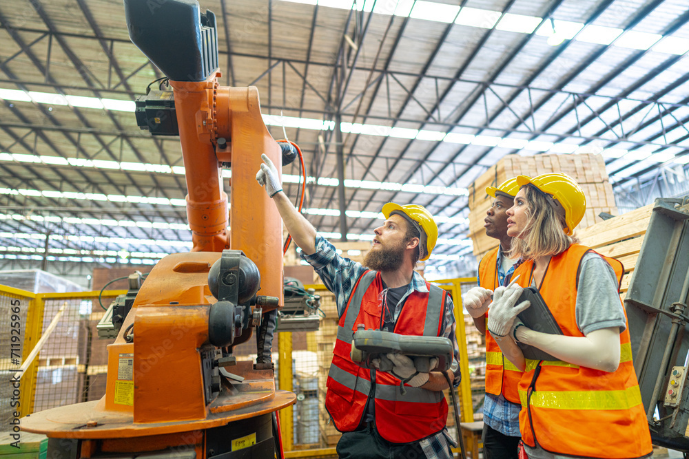 team Engineers standing by robotic arm and operating machine in factory. worker man control on tablet. Workers work at heavy machine robot arm. High-tech robot with a remote system in Wood factory.