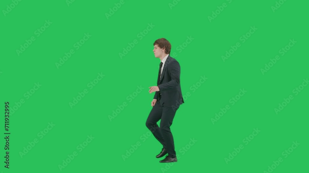 Profile view of male model in suit isolated on chroma key green screen background. Positive young businessman in blue suit walking and dancing coolly. Profile view of male model in suit isolated on chroma key green screen background. Positive young businessman in blue suit walking and dancing coolly.