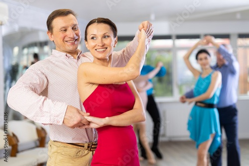 Group of different ages active people in festive clothes dancing dance movements in modern studio